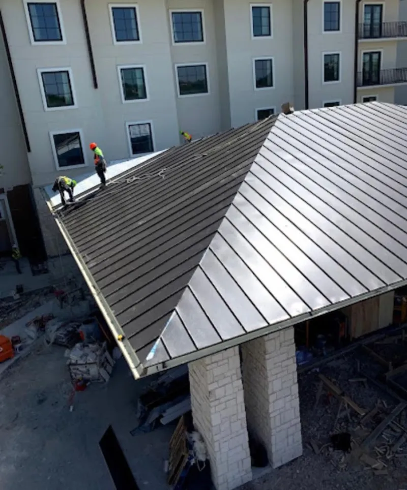 Crew installing standing seam metal roof panels on a commercial project in Ithaca